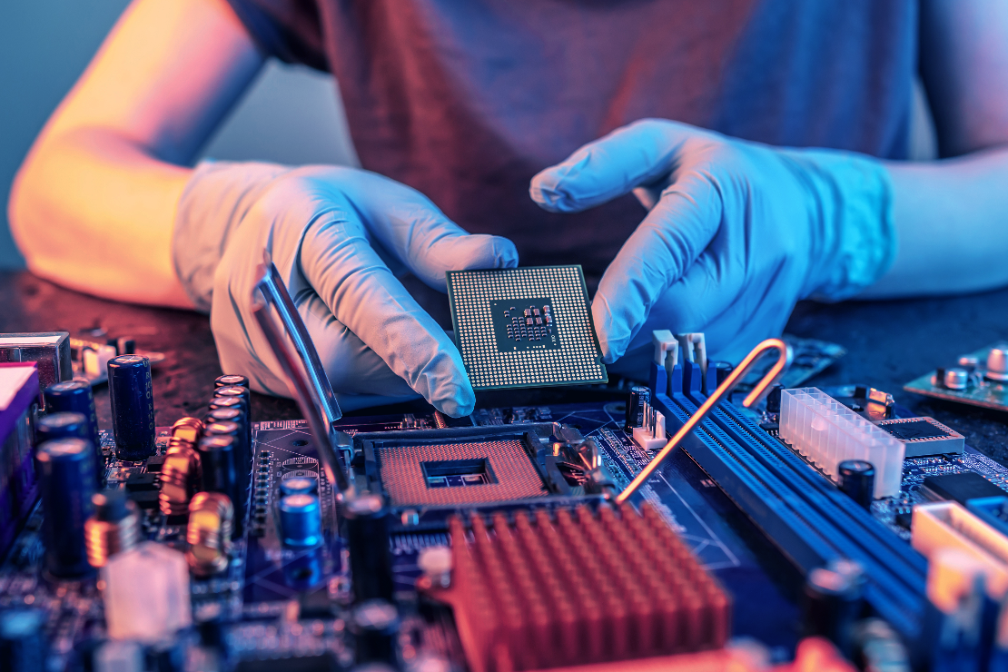 A person wearing gloves and holding a semiconductor, working on a semiconductor technology and manufacturing project.
